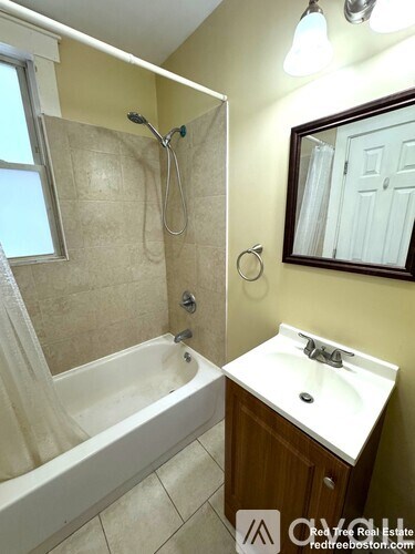 A bathroom with a tub, sink, mirror, and a window.