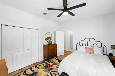 A bedroom with a bed, dresser, and ceiling fan.