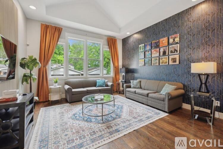 A living room with a grey couch, a coffee table, and a wall with pictures on it.
