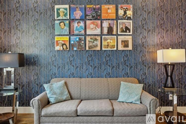 A grey couch with two pillows sits in front of a wall with a collection of framed pictures.