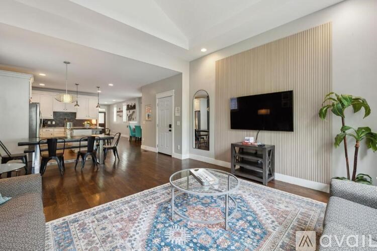 A living room with a rug, a sofa, a table, and a TV mounted on the wall.