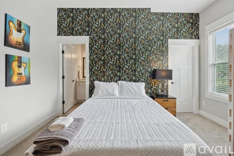 A bedroom with a large bed and a guitar picture on the wall.