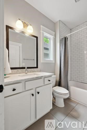 A white bathroom with a toilet, sink, and mirror.