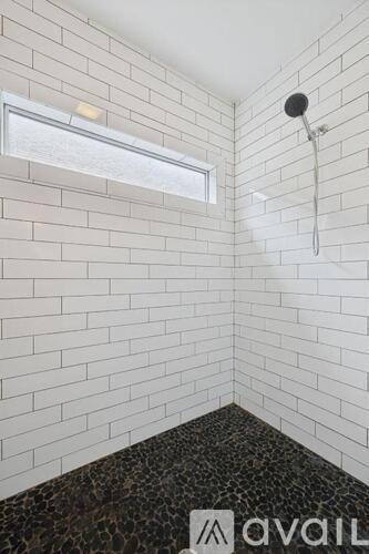 A bathroom with a shower head and a window.