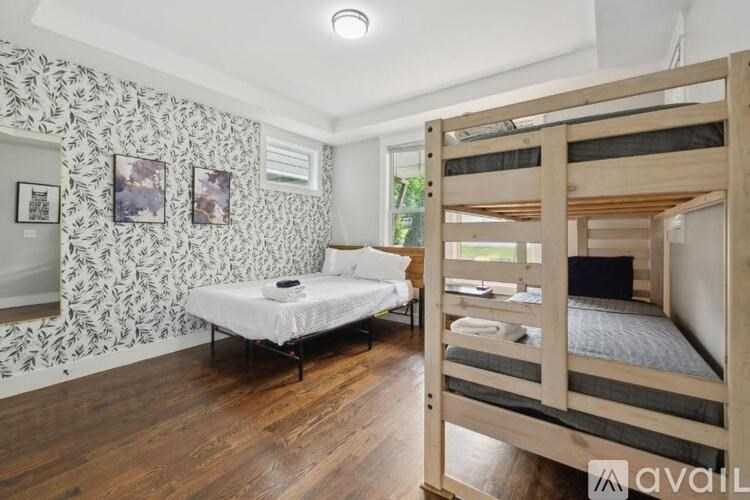 A bedroom with a wooden floor and a wallpapered wall with a floral pattern.