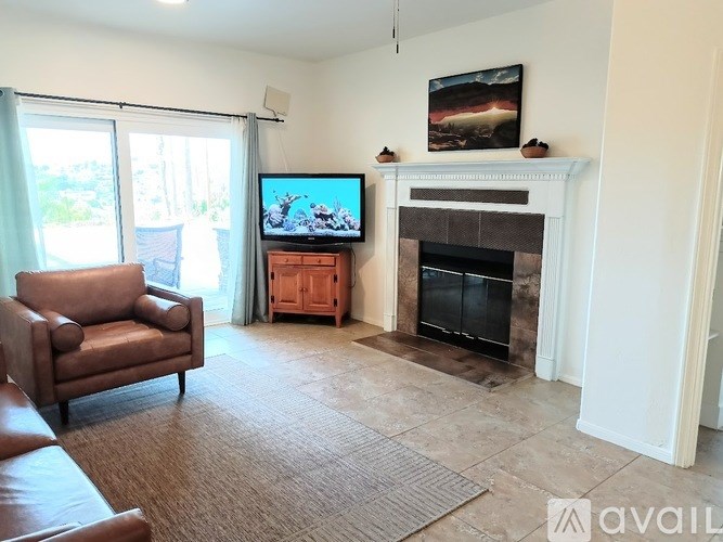 A living room with a brown leather chair, a white fireplace, and a flat screen TV mounted on the wall.