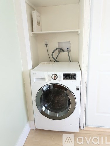 A white washing machine is installed in a small cabinet.