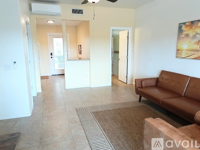 A living room with a brown couch and a painting on the wall.