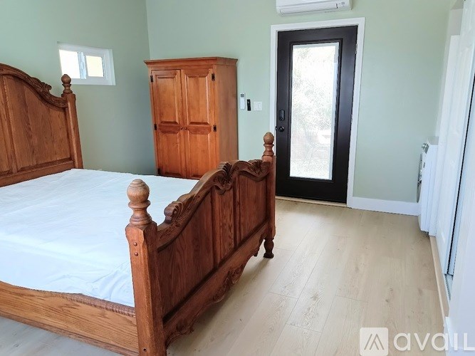 A bedroom with a bed, wooden dresser, and a door.