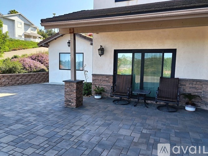 A patio with a table and chairs is in front of a house.