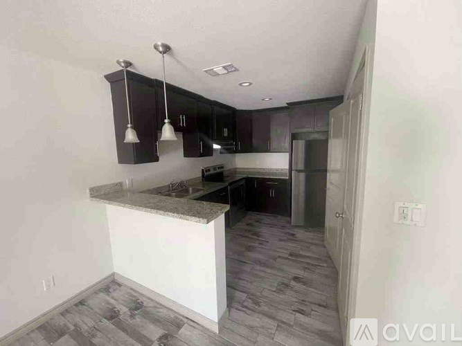 A kitchen with a marble countertop and dark wood cabinets.
