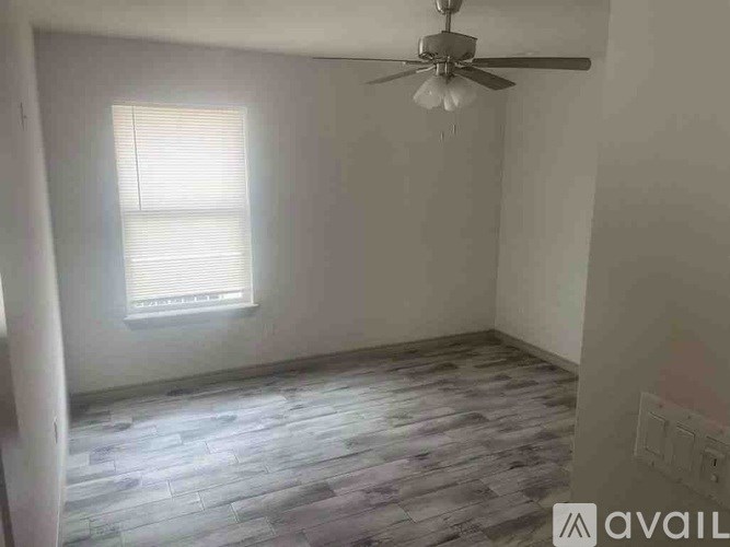 A room with a ceiling fan and a window with blinds.
