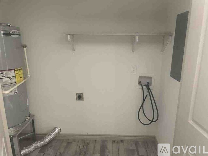 A room with a wall-mounted shower head and a pipe running along the floor.
