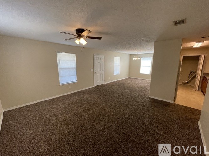 A spacious room with a carpeted floor and a ceiling fan.