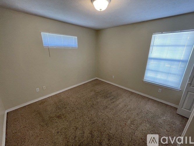 A room with a carpeted floor and a window with blinds.