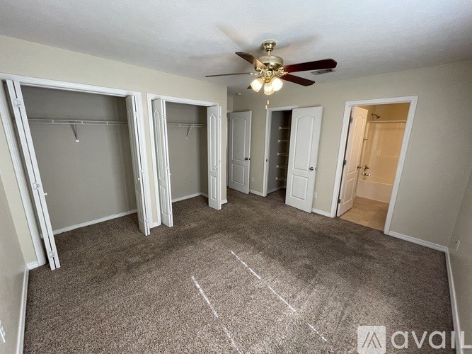 A room with a carpeted floor and a ceiling fan.