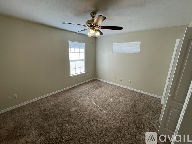 A room with a ceiling fan and carpeted floor.