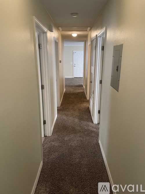 A long hallway with carpeted floors and white walls.