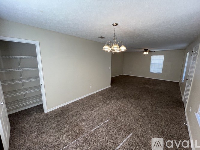 A room with a carpeted floor and a chandelier hanging from the ceiling.