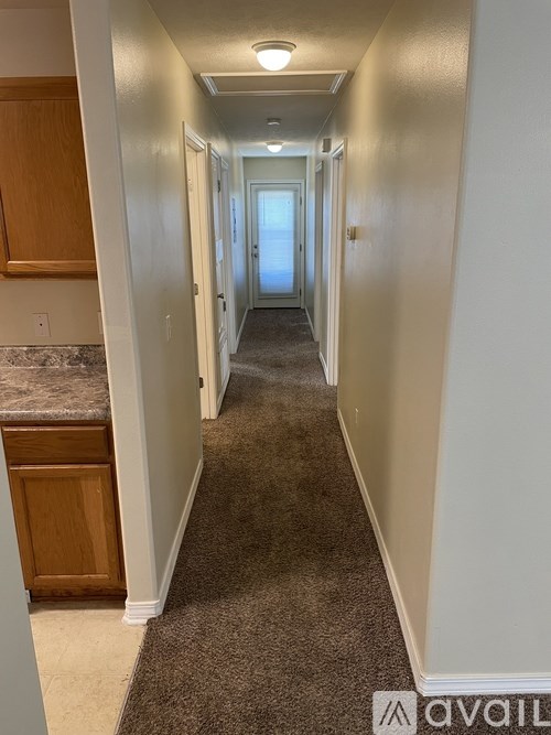 A long hallway with carpeted floors and white walls.