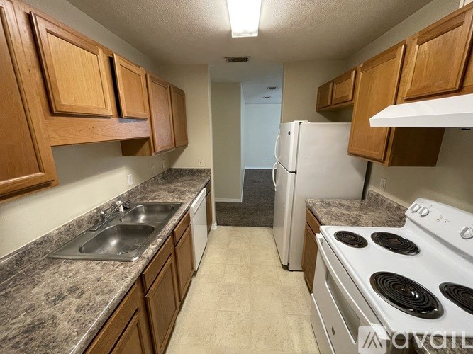 A kitchen with a white stove and wooden cabinets.