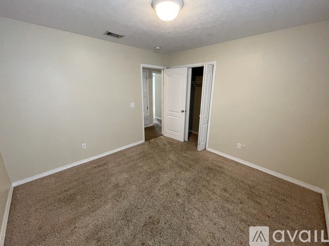 A carpeted room with a doorway leading to another room.