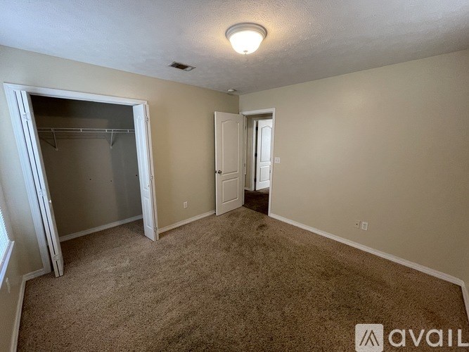 A room with a carpeted floor, a white door, and a white closet door.