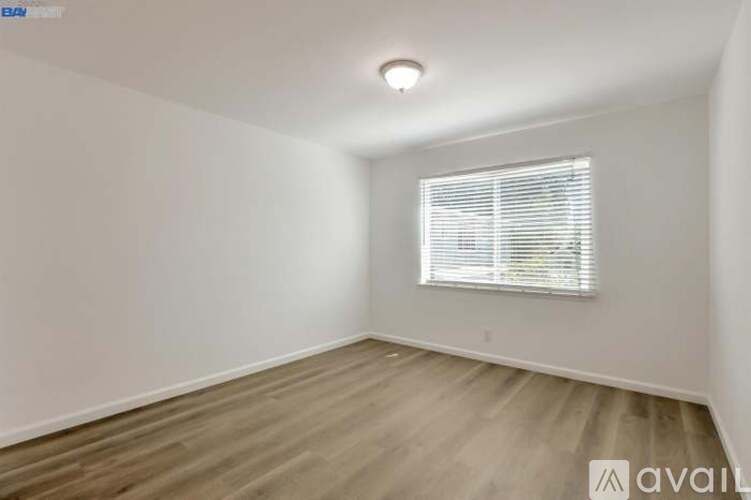 A room with a window and wooden flooring is available for rent.