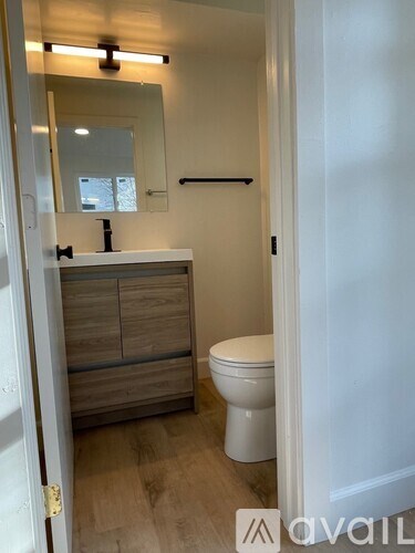 A bathroom with a toilet, sink, and mirror.