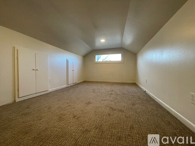 A room with carpeted floor and a window with blinds.