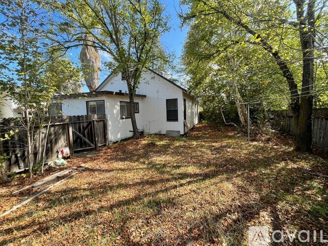 A white house with a brown roof surrounded by trees.