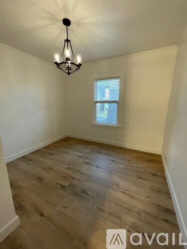 A room with wooden flooring and a chandelier hanging from the ceiling.