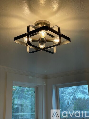 A modern chandelier with a glass shade and metal frame hangs from a ceiling.