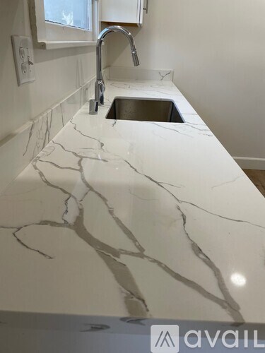 A white marble countertop with a sink and faucet.