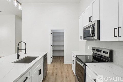 A kitchen with white cabinets and black appliances.