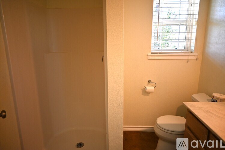 A bathroom with a toilet, sink, and a window.