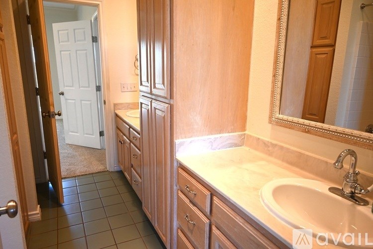 A bathroom with a sink, mirror, and wooden cabinets.