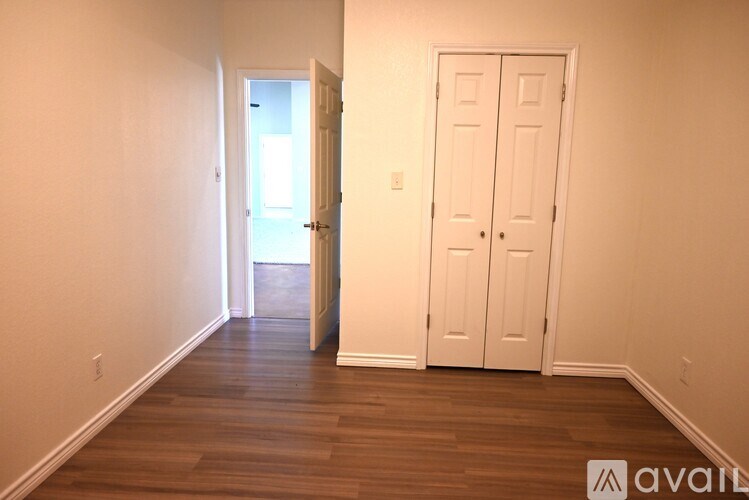 A room with a white door and wooden floors.