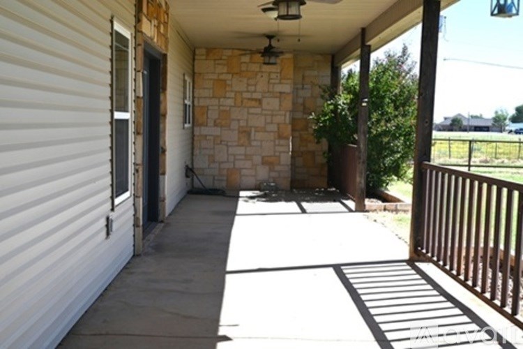 A patio with a white wall and a black railing.