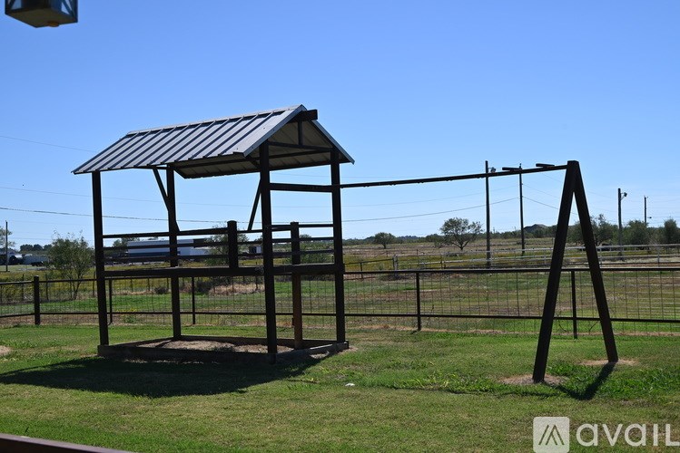 A shelter with a metal roof is situated in a grassy area.