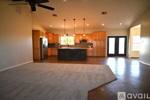 A spacious kitchen with wooden cabinets and a black refrigerator is available for rent.