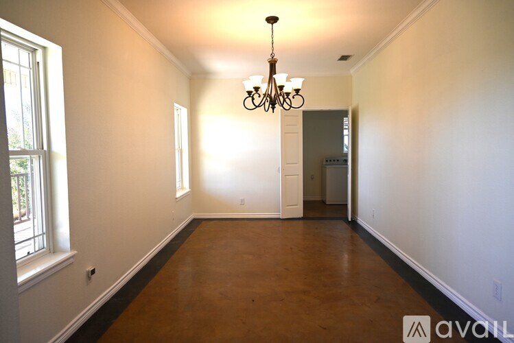 A room with a chandelier and a door at the end.