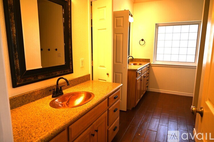 A bathroom with a sink, mirror, and wooden cabinets.