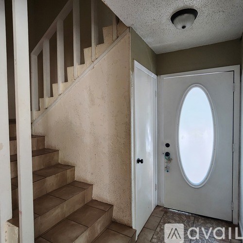 A staircase with a white railing leads to a door with a round window.