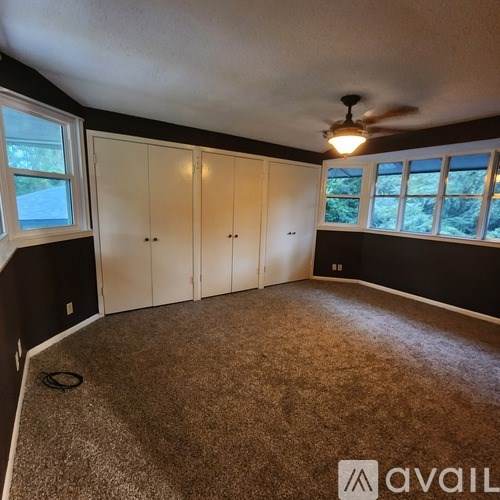 A room with a carpeted floor and a ceiling fan.