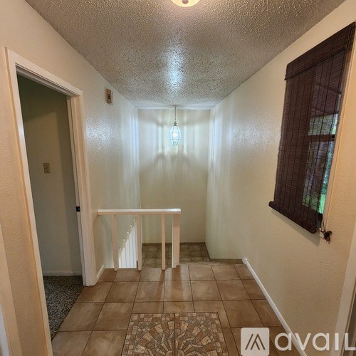 A hallway with a tiled floor and a light hanging from the ceiling.