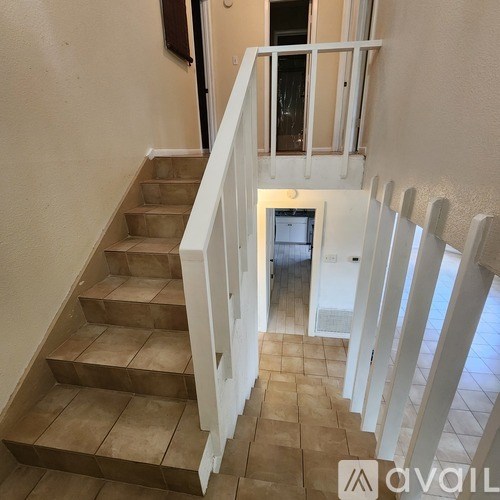 A staircase with a white railing and beige steps leads to a door.