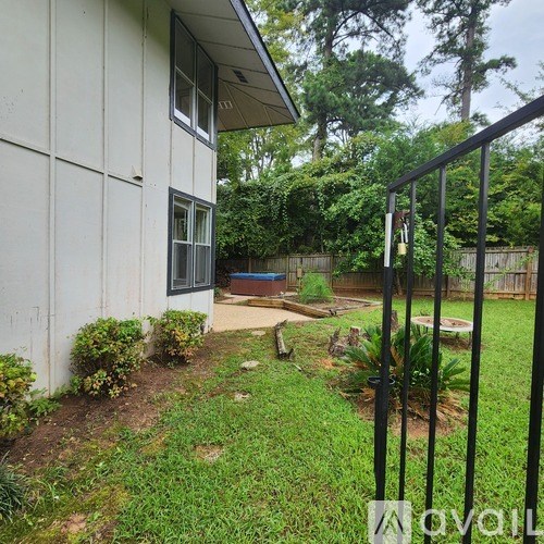 A white house with a black fence and a small garden in front.