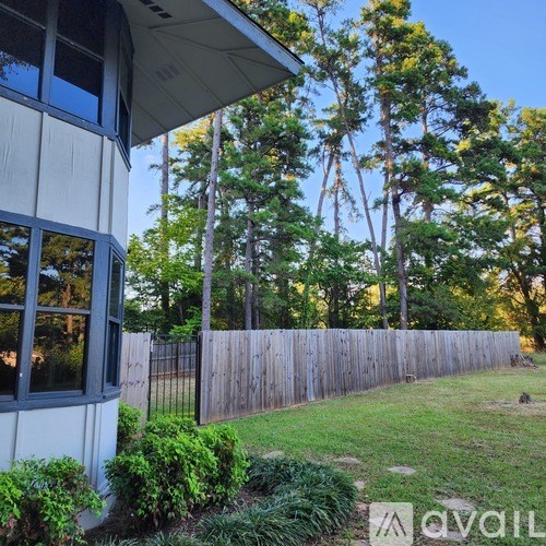 A house with a fence and trees in the background.