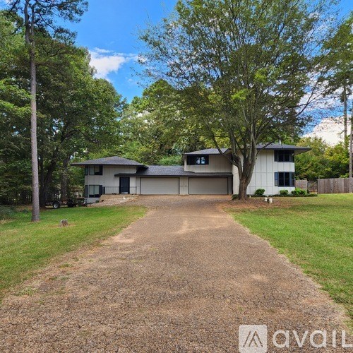 A house with a driveway in front of it surrounded by trees.